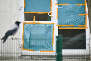 Planen decken an einer Unterkunft für Geflüchtete die beschädigten Scheiben einer Tür ab. Das Übergangswohnheim für Asylsuchende wurde in der Nacht des vergangenen Samstags angegriffen.