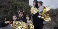 Flüchtlingskinder und eine Mutter in Wärmedecken gewickelt