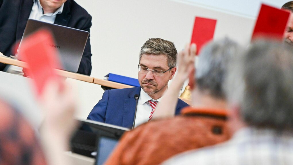 Mike Schubert sitzt Stadtverordneten gegenüber, die eine rote Karte zeigen