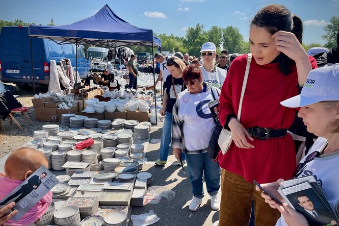 Clotilde Armand in einer roten Jacke auf einem Markt