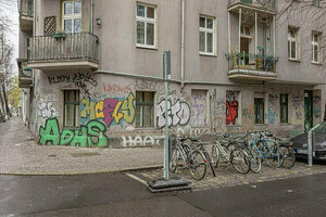 Eine mit Graffiti versehene Hausecke mit mehreren Fahrrädern davor.