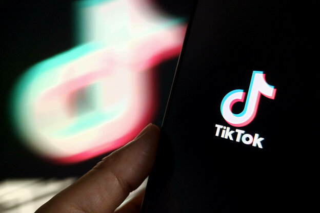 Eine Person hält ein Handy in der Hand, auf dem das TikTok-Logo zu sehen ist