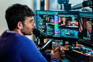 Der Streamer sitzt im blauen Pulli vor vielen Bildschirmen und spricht ins Mikro
