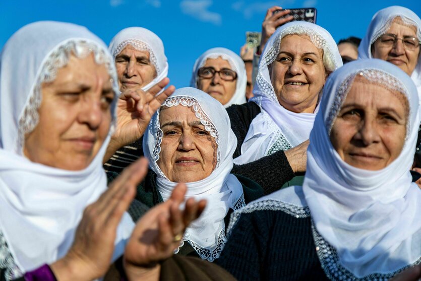 Frauen mit weißen Kopftüchern stehen zusammen und applaudieren