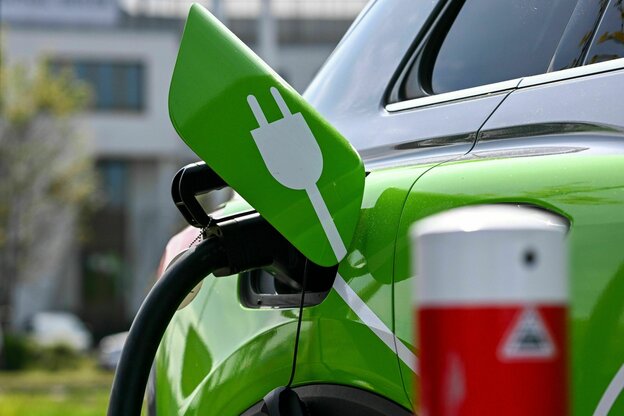 Ein Elektroauto wird an einer Ladesäule auf einem Parkplatz geladen