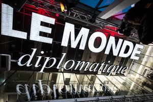 Die legendäre alte Leuchtreklame von Le Monde diplomatique hängt heute von der Decke des Speisesaals der tat Kantine im taz-Neubau – Symbol kritischer Öffentlichkeit, fotografiert bei einer Abendveranstaltung.