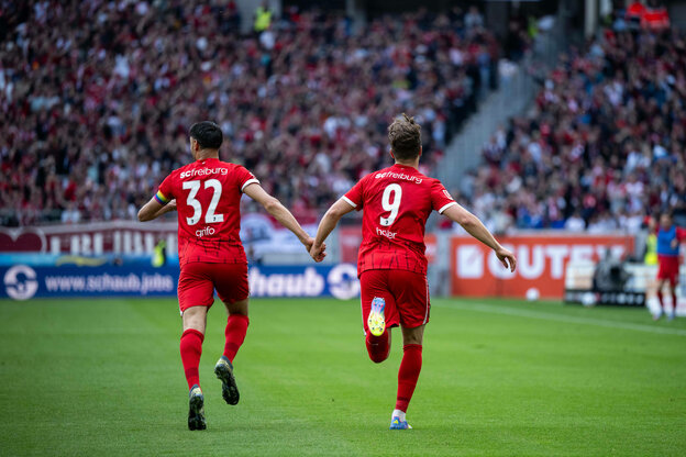 Grifo und Höler von hinten zu sehen, wie wie Hand in Hand Richtung Fankurve laufen