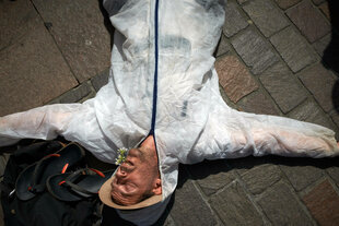 Eine Person liegt in einem weißen Schutzanzug auf dem Boden