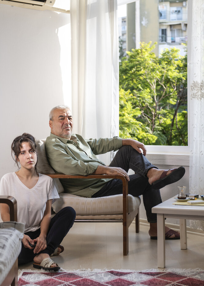 Porträt von zwei Personen in einem Wohnzimmer.