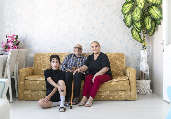 Porträt von drei Personen in einem Wohnzimmer.