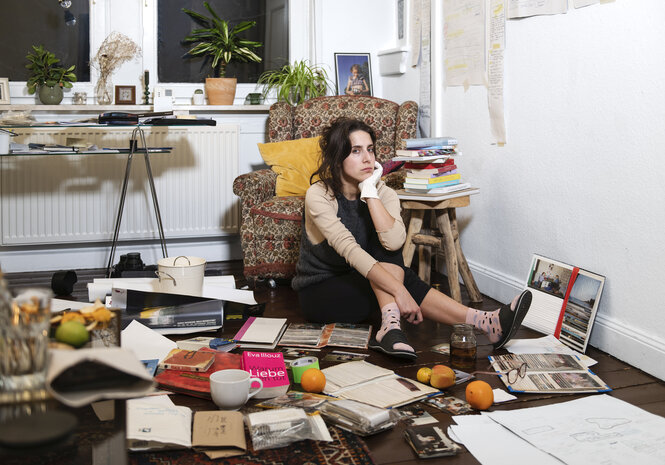 Porträt von einer Person mit vielen Büchern und anderen Sachen.