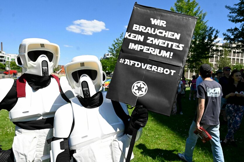 Zwei als Star-Wars-Stormtrooper verkleidete Personen halten bei einer Demo ein Schild hoch, auf dem steh: "Wir brauchen kein zweites Imperium! AfD Verbot Jetzt"