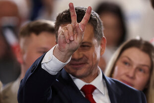 Rafał Trzaskowski steht in einer Menschenmenge und macht das Victory-Zeichen