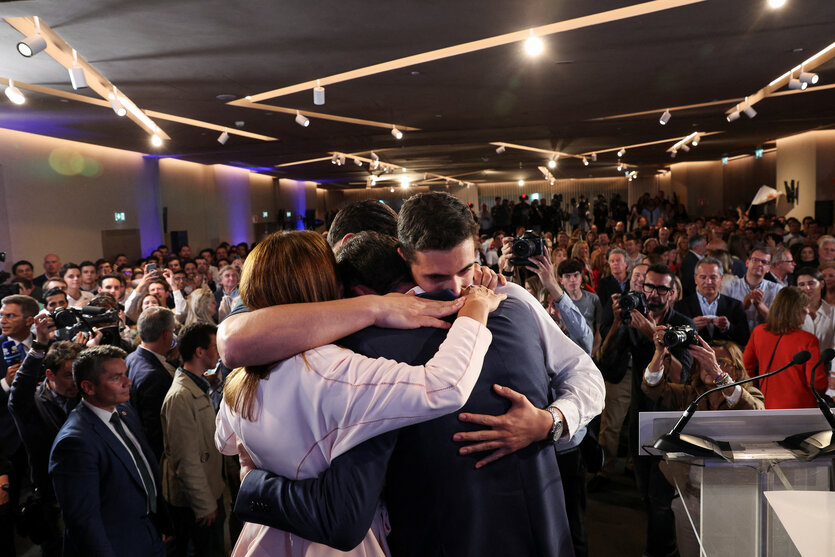 Luís Montenegro steht dicht umarmt mit anderen Personen zusammen auf einer Bühne