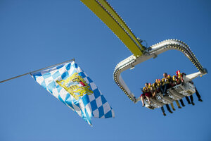 Ein Fahrgeschäft auf dem Oktoberfest vor einer Bayernflagge