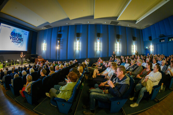 Man sieht einen Kinosaal des Filmfestivals 2024. Mehrere Personen sitzen in dem Saal und schauen auf die Bühne.