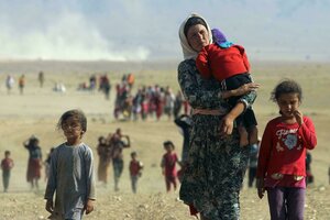 Eine Frau trägt ein Kleinkind auf dem Arm und läuft zusammen mit anderen Kindern durch eine wüstenähnliche Landschaft, weitere Personen folgen in der Ferne