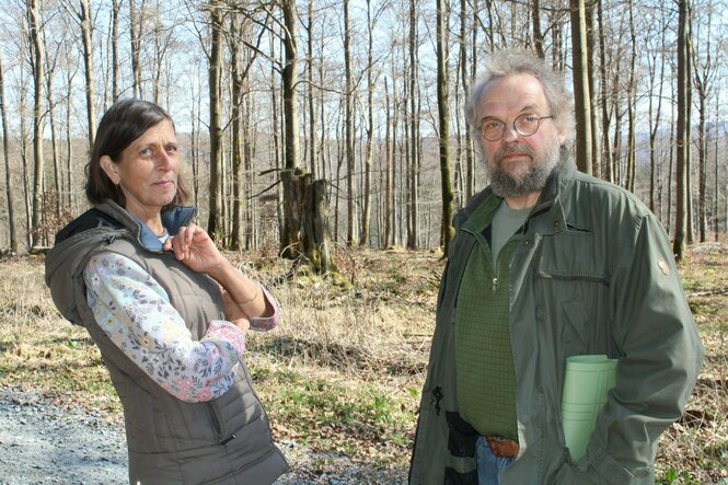 Eine Frau und ein Mann in legerer Kleidung stehen in einem Wald