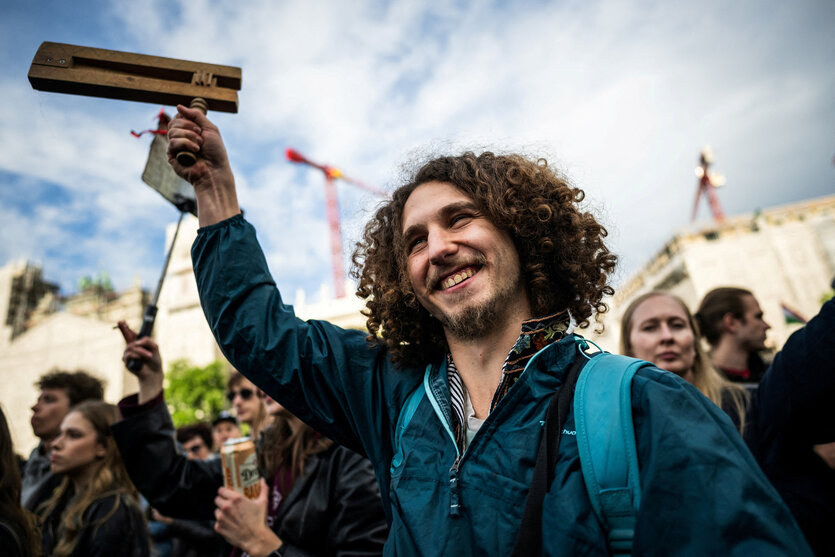 Eine Person mit Rassel steht lachend in einer Menschenmenge