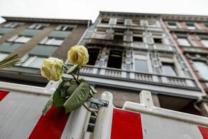 Eine Rose an einer Absperrung vor einem ausgebrannten Wohngebäude