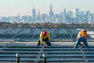 Elektriker installieren im New Yorker Stadtteil Queens Solarpaneele auf dem Dach der Garage des Terminals B am Flughafen LaGuardia