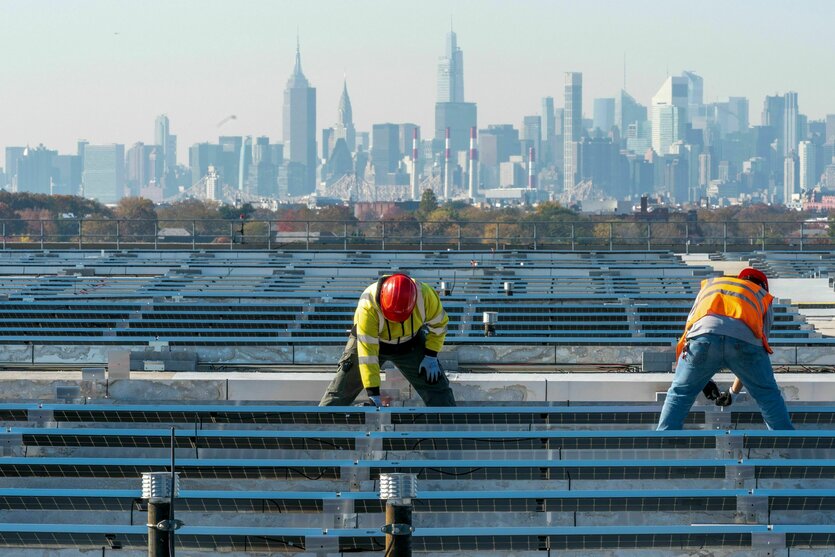Elektriker installieren im New Yorker Stadtteil Queens Solarpaneele auf dem Dach der Garage des Terminals B am Flughafen LaGuardia