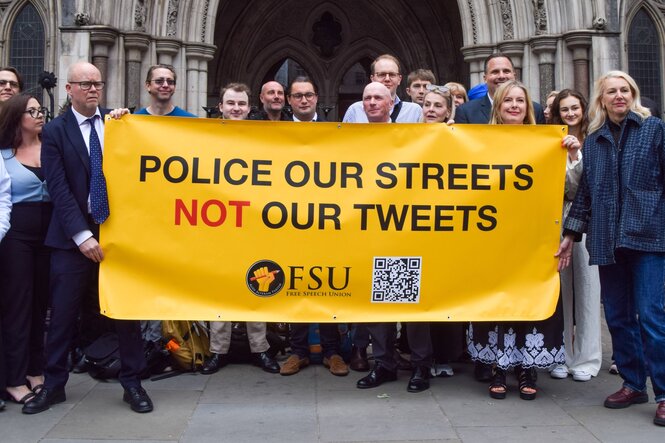 Ein gelbes Plakat "Police our streets Not our tweets" wird von einer Menge in die Höhe gehalten