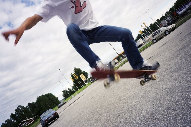 Ein junger mensch fährt auf einem Parkplatz mit seinem Skateboard