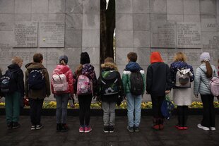 Kinder stehen vor einem Mahnmal
