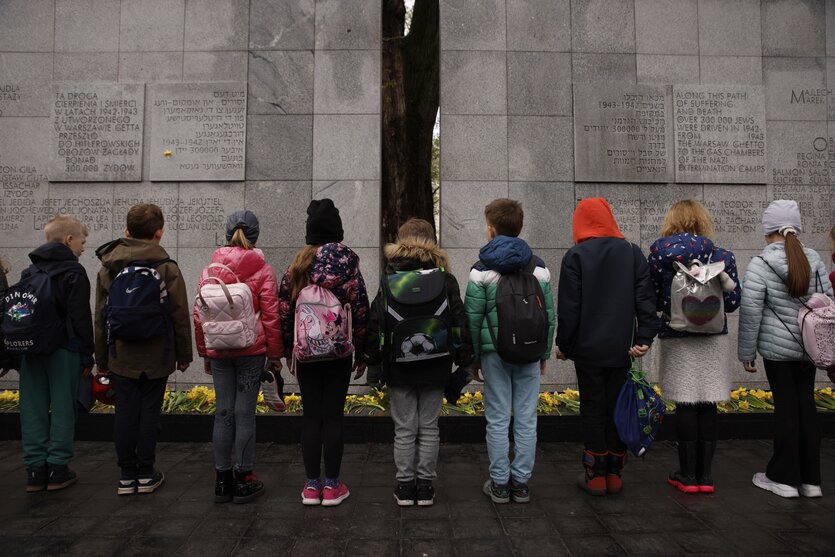 Kinder stehen vor einem Mahnmal