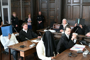 Die drei Angeklagten sitzen mit ihren Anwälten in einem Gerichtssaal des Strafjustizgebäudes in Hamburg und verdecken ihre Gesichter mit Aktendeckel und Kleidung.