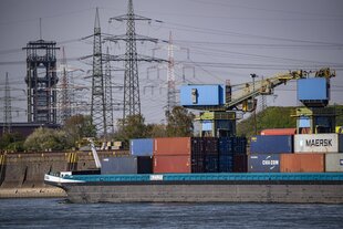 Ein Frachtschiff auf dem Rhein, im Hintergrund das Fördergerüst der stillgelegten Zeche Walsum
