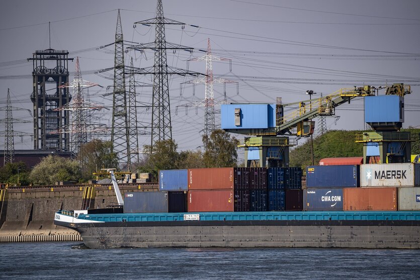 Ein Frachtschiff auf dem Rhein, im Hintergrund das Fördergerüst der stillgelegten Zeche Walsum