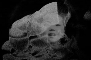 Still aus einem Schwarz-weiß-Film: Hinter transparenten Schwaden ist das Gesicht eines Kindes zu erkenne, das lacht.