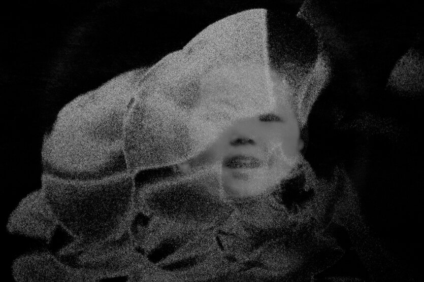 Still aus einem Schwarz-weiß-Film: Hinter transparenten Schwaden ist das Gesicht eines Kindes zu erkenne, das lacht.