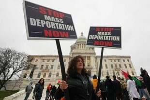 Eine Frau hält ein Protestschild "Stop Mass deportation now"