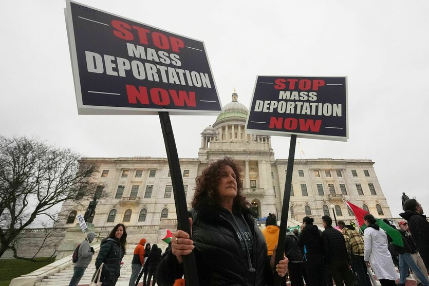 Eine Frau hält ein Protestschild "Stop Mass deportation now"
