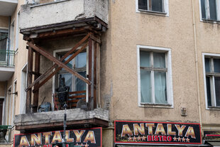 Abgestützter Balkon mit einer Hexen-Holzstaue