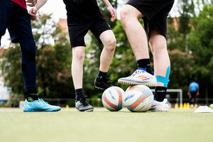 Fußballerbeine und Bälle auf einem Sportplatz