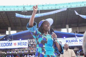 Martha Karua hebt einen Arm, sie steht in einem Sportstadion und spricht in ein Mikrofon