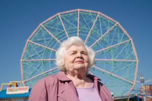 Eine ältere Frau steht vor einem Riesenrad