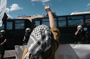 Eine Frau mit Kufiyah steht vor Polizisten
