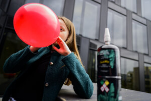Eine Jugendliche zieht an einem großen roten Ballon mit Lachgas