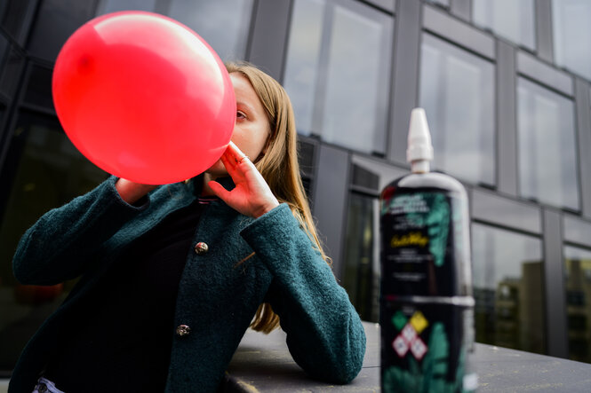 Eine Jugendliche zieht an einem großen roten Ballon mit Lachgas
