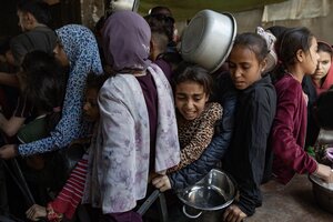 Junge Frauen stehen dicht gedrängt in einer Schlange an, sie halten Kochtöpfe in den Händen, ein Mädchen wird gequetscht