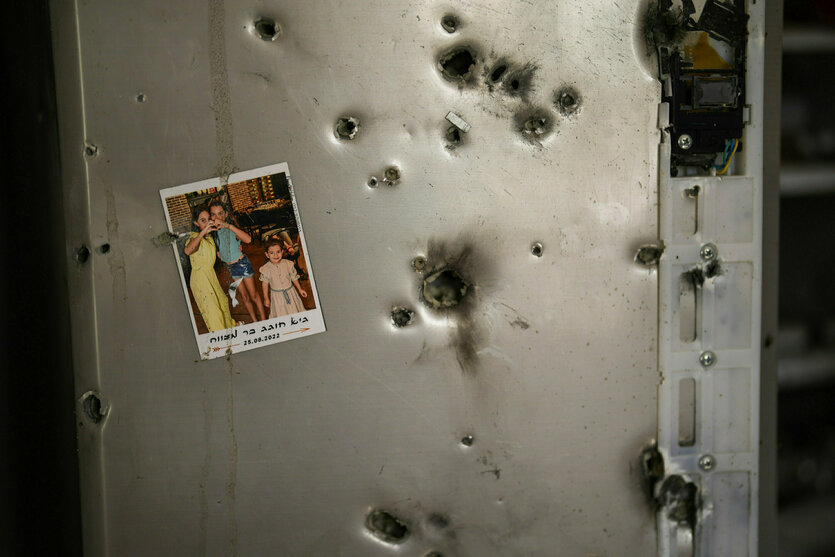 An einem mit Einschüssen übersäten Kühlschrank hängt ein Familienbild