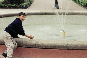 Ein Junge spielt an einem Brunnen