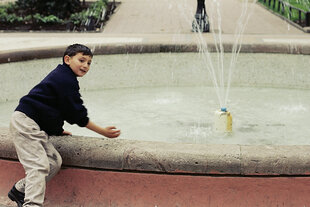 Ein Junge spielt an einem Brunnen