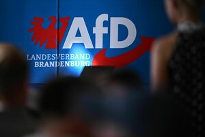 Teilnehmende sitzen in der Auftaktveranstaltung der AfD in Brandenburg zur Landtagswahl vor dem Parteilogo