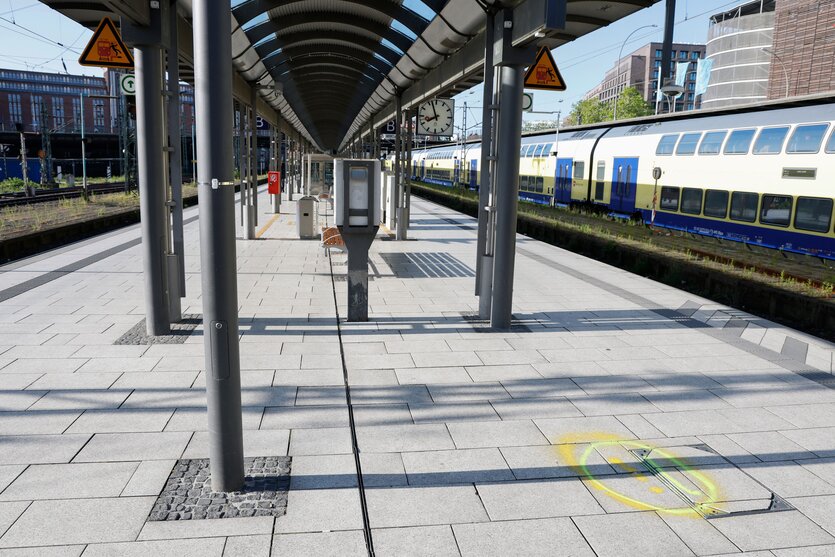 Ein Bahnsteig des Hamburger Hauptbahnhofs außerhalb der Bahnhofshalle. Auf dem Boden eine gelbe Markierung, auf dem Nachbargleis ein Regionalzug